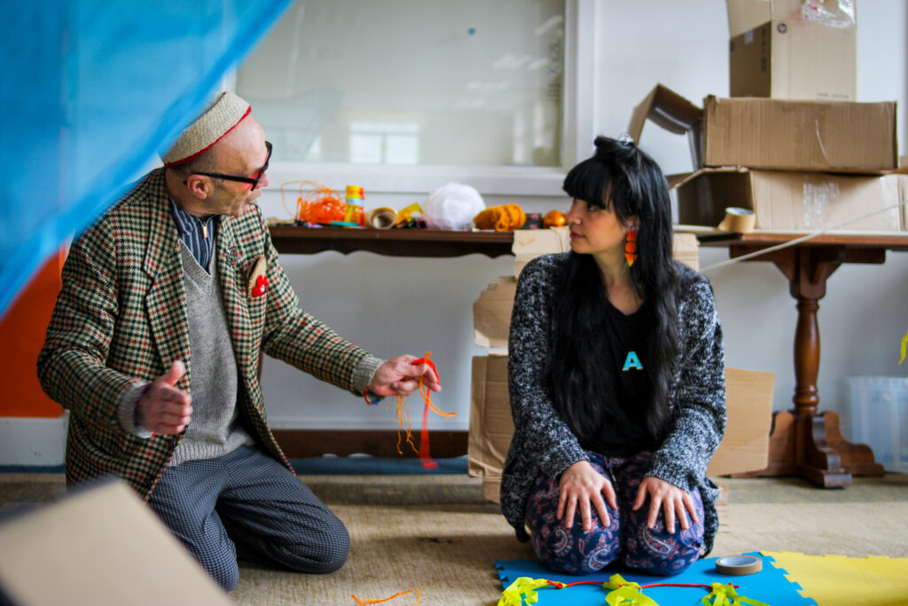 Two people kneeling chatting whilst they work with different materials for den making