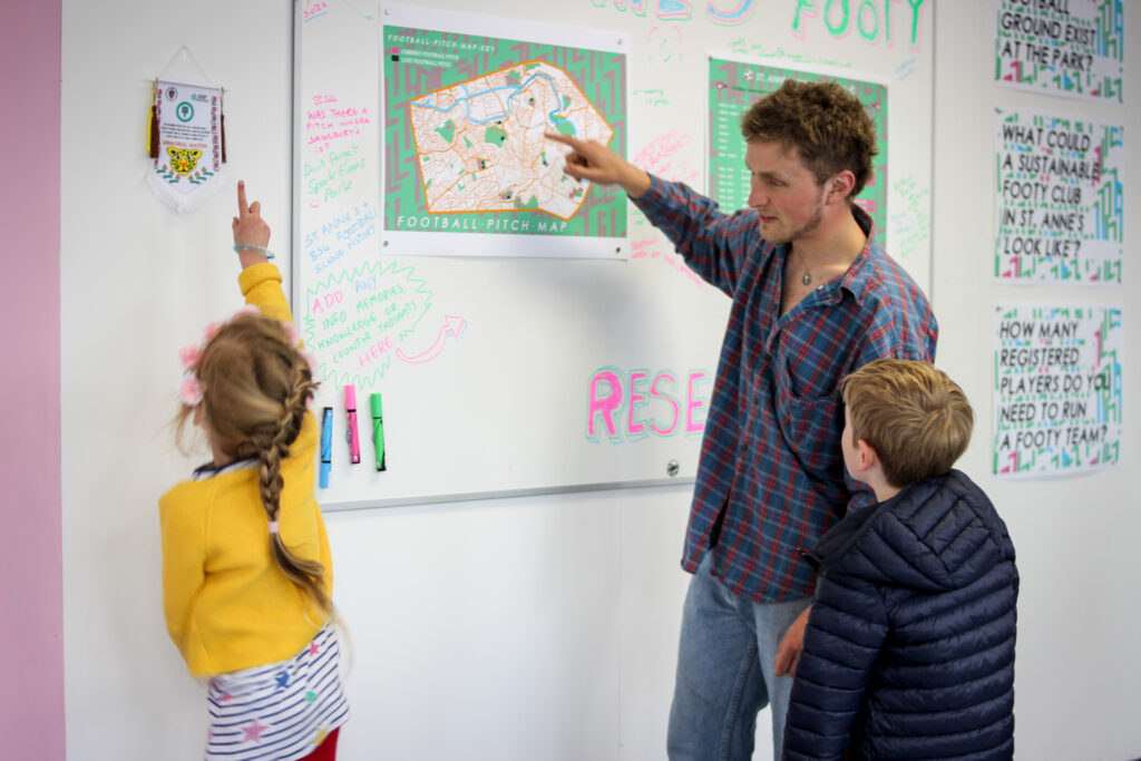 An artist talking to young children in the exhibition space at St Anne's House