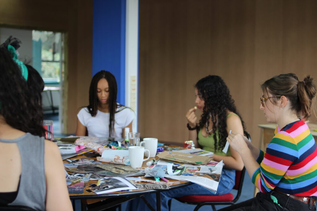 A group of young people sat around making collage at St Anne's House
