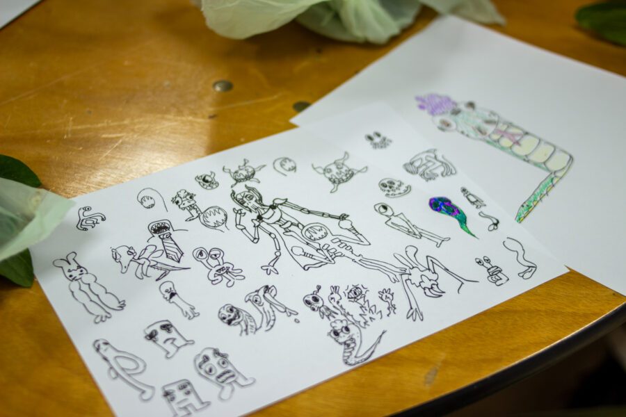 Sketched and doodles of aliens and characters on paper at St Anne's House.