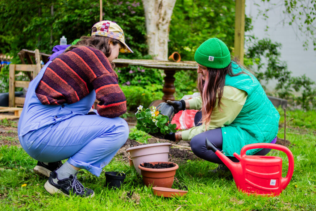 Two people in colourful clothes and hats potting plants