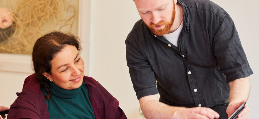 A man showing a woman something on an ipad for a workshop.