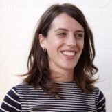 A woman smiling and looking to the side for their headshot.