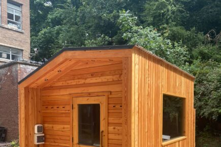 An outdoor sauna structure outside St Anne's House with trees behind.