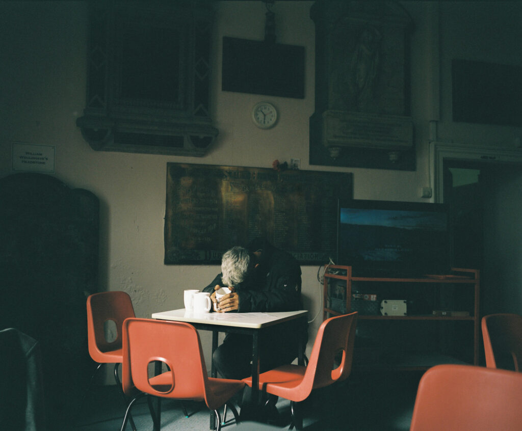 A homeless man falls asleep, after receiving a hot drink at the drop-in centre St Hilda's church, South Shields, September 2023.