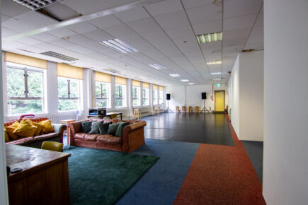 A bright open plan room with sofas and a rehearsal area.